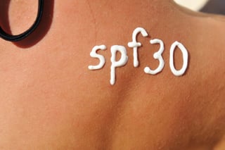 Tan woman with UV damage and white spf 30 sunscreen letters