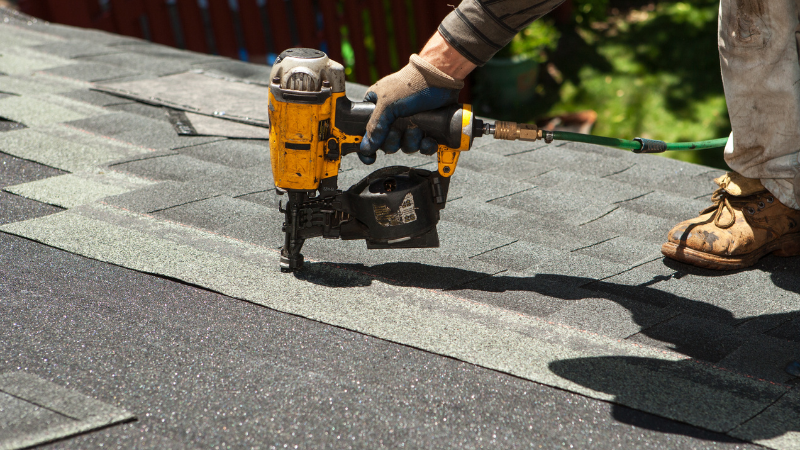 nail gun on roof installing shingles